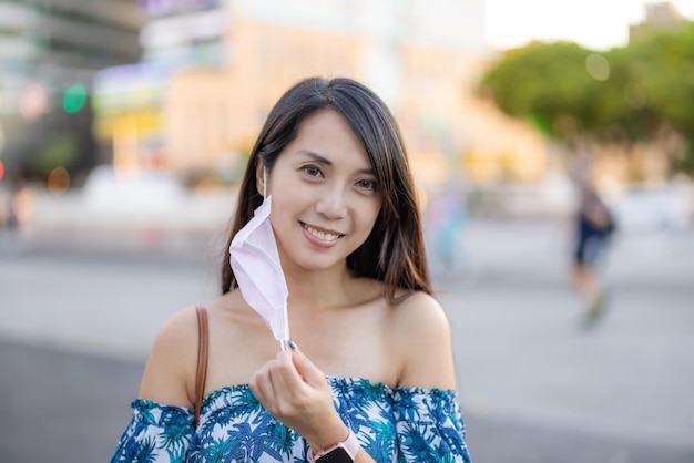 Woman take off the face mask in the city