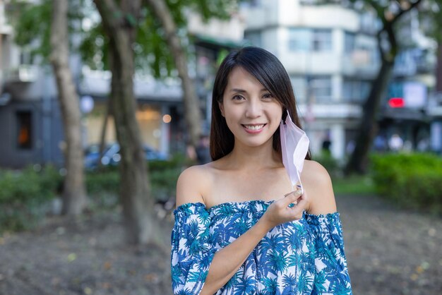 Woman take off the face mask and smile to camera in city