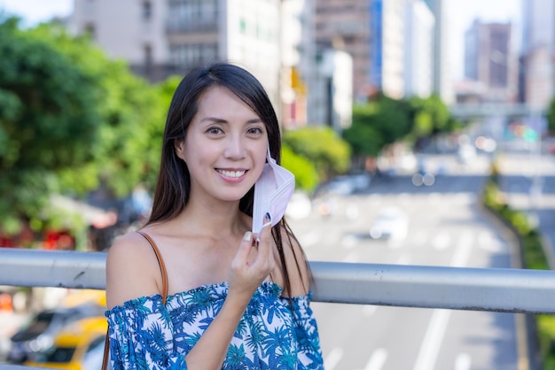 女性が市内でカメラに向かってマスクを脱いで笑顔を浮かべる