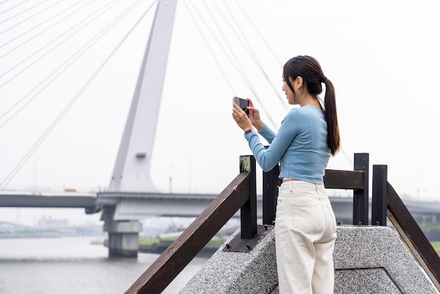 女性が街で携帯電話で写真を撮る