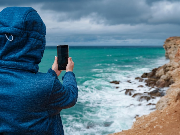 スマートフォンで海の写真を撮る女性