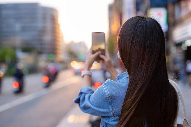 台北市の通りで写真を撮る女性