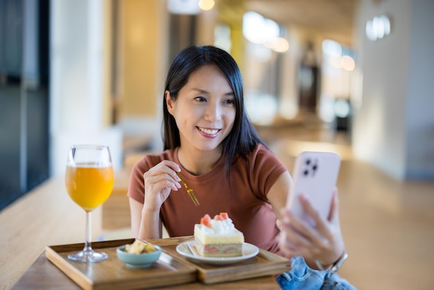 Женщина делает селфи на мобильном телефоне с послеобеденным чаем в кафе