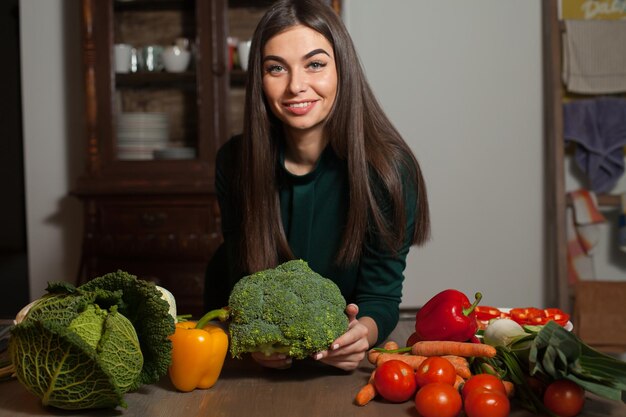 野菜たっぷりのテーブルでブロッコリーを手に取る女性