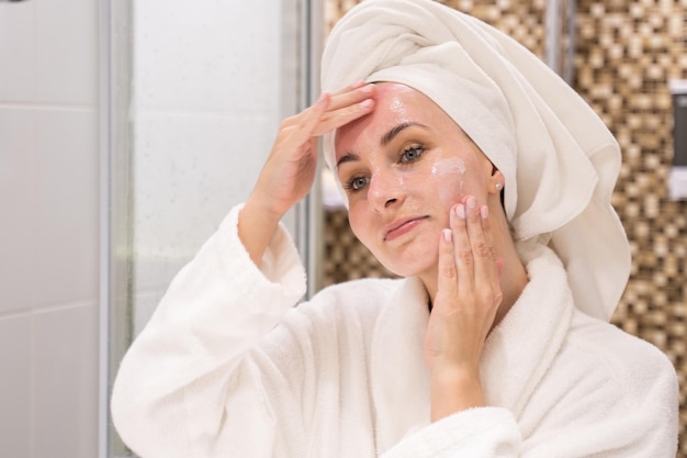 Woman takes care of face applying gel cleanser in bathroom