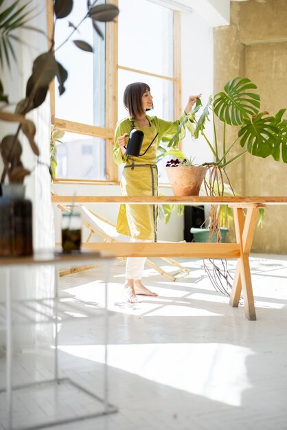 女性は屋内で緑の植物の世話をします