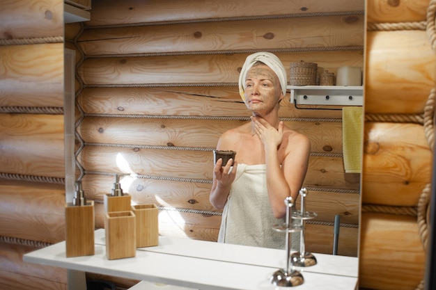 A woman takes care of herself standing in the bathroom of a
wooden house ecofriendly selfcare natura...