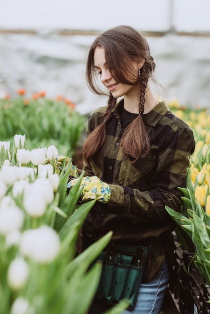 Женщина ухаживает за цветами тюльпанов в саду. Весна и лето. счастливая женщина-садовник с цветами.