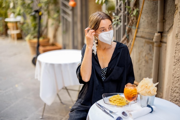 Woman takes off face mask while sitting at italian restaurant
outdoors