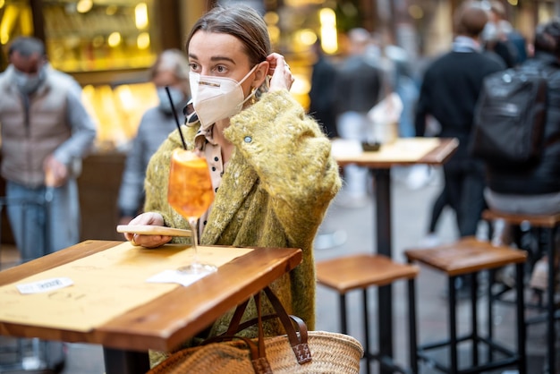 Woman takes off medical mask while sitting at outdoor cafe