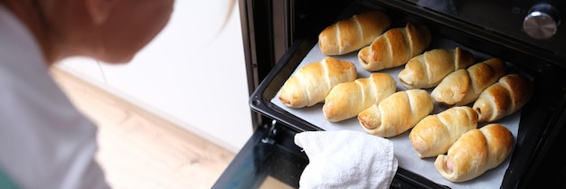 Foto la donna tira fuori la teglia di croissant cotti dal primo piano del forno