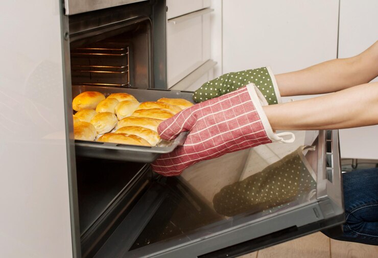 Photo 女性がキッチンのクローズアップでオーブンから準備済みのパイを取り出します