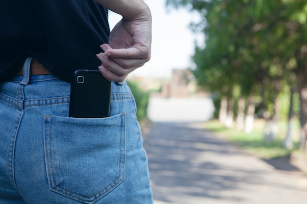 La donna prende il telefono dalla tasca nel parco