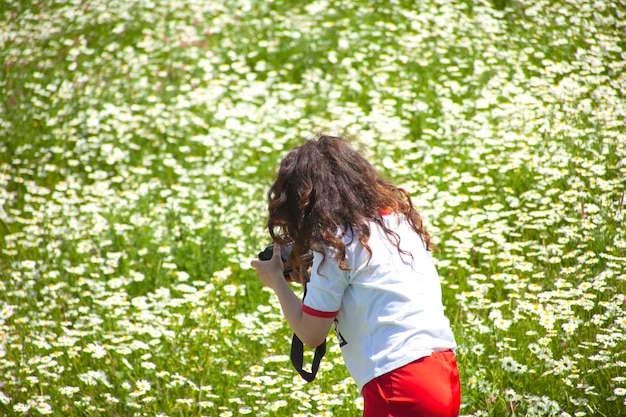 여자는 카모마일 밭에서 사진을 찍는다