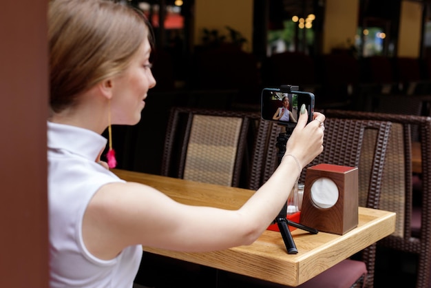 A woman takes a selfie on a smartphone in a cafe on a walk in the summer