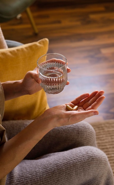 Woman takes vitamin pills at home close up