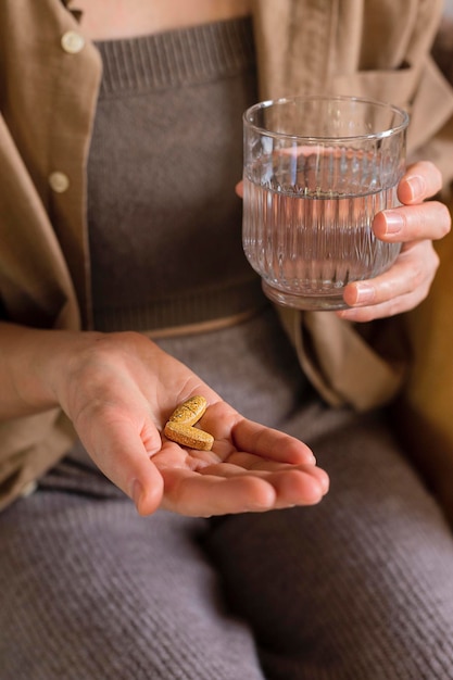 Woman takes vitamin pills at home Close up