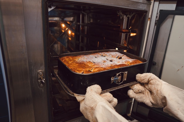 Foto donna che toglie una torta dal forno