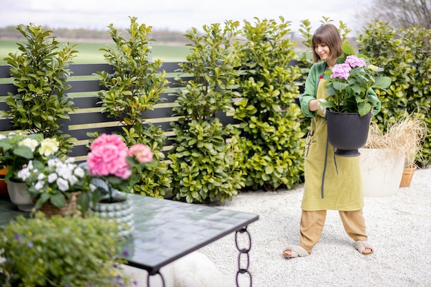 Foto donna che si prende cura dei fiori in giardino