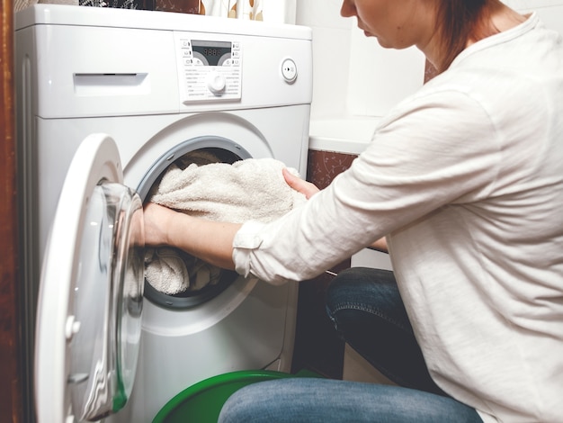 Женщина берет чистое белье из стиральной машины