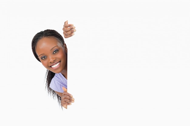 Woman taking a look around the corner on white background