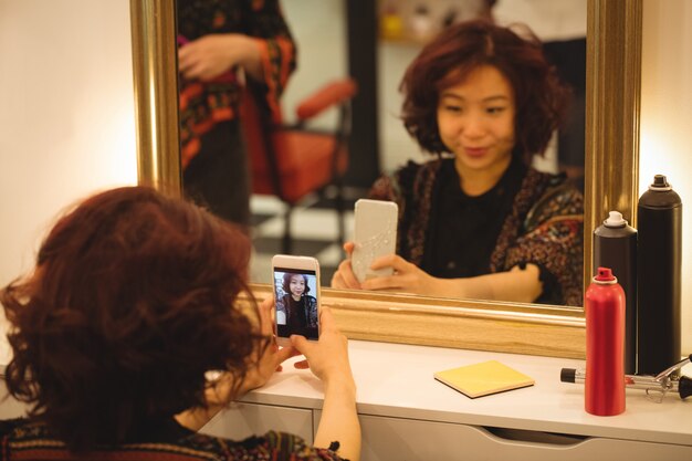 Woman taking mirror selfie at hair salon