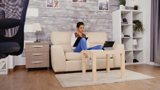 Woman taking notes on clipboard during a video call while working from home.