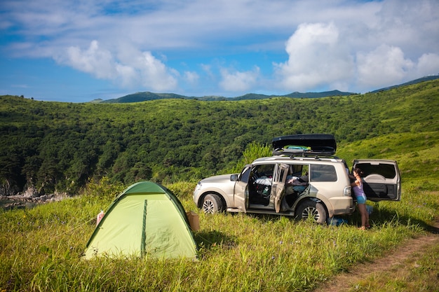 woman taking off tourist equipment the car trunk at tourist camp