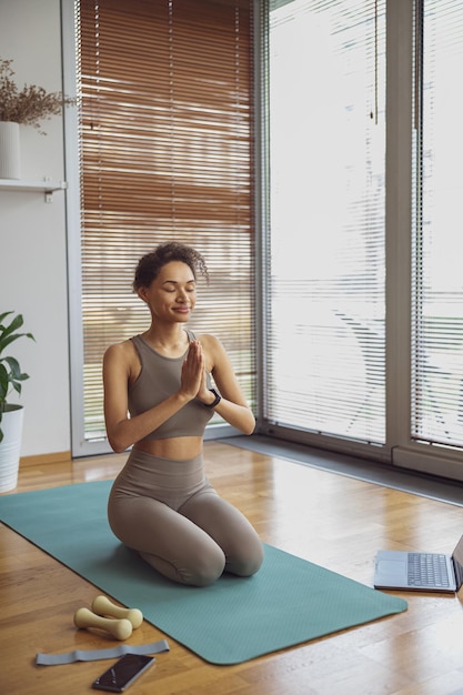 Woman taking online yoga class from home female engaged in webcam meditation practice on computer