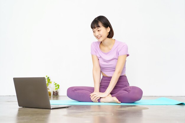 A woman taking an online yoga lesson using a laptop