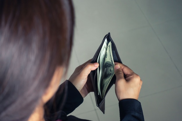 Женщина достает доллар банкноты из кошелька