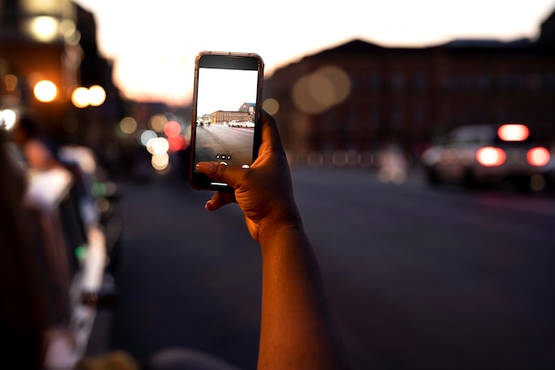 写真 スマートフォンで街の明かりで夜に写真を撮る女性