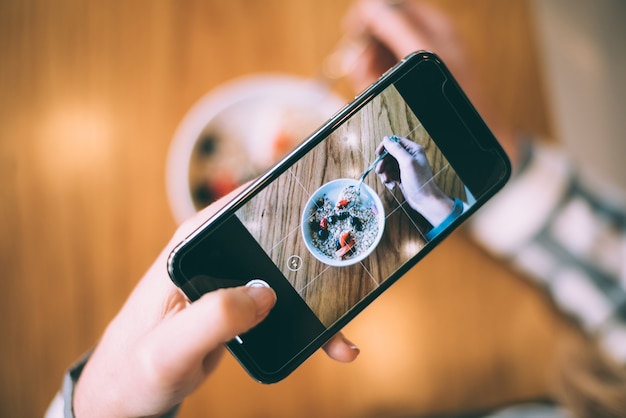 Photo woman taking photo of a bowl breakfast oats and fruit