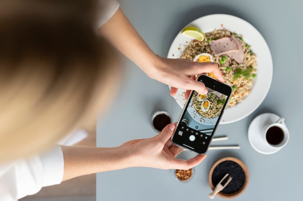 Photo woman taking photo of plate of noodles