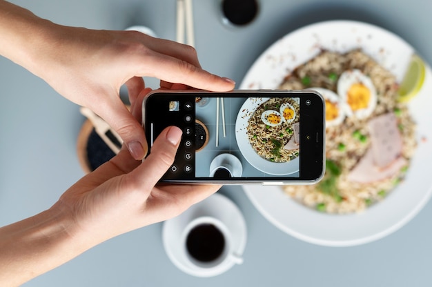 麺のプレートの写真を撮る女性