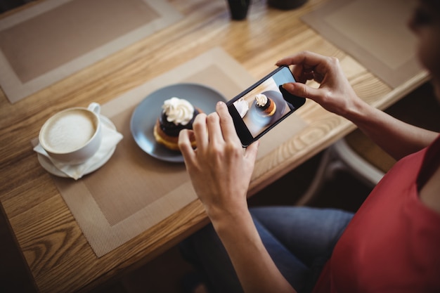 Woman taking a photo of sweet food from mobile phone