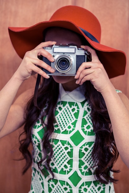 Photo woman taking photograph with camera against wooden wall