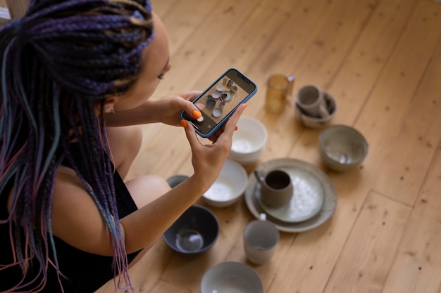 Photo woman taking photos of ceramic kitchenware at home