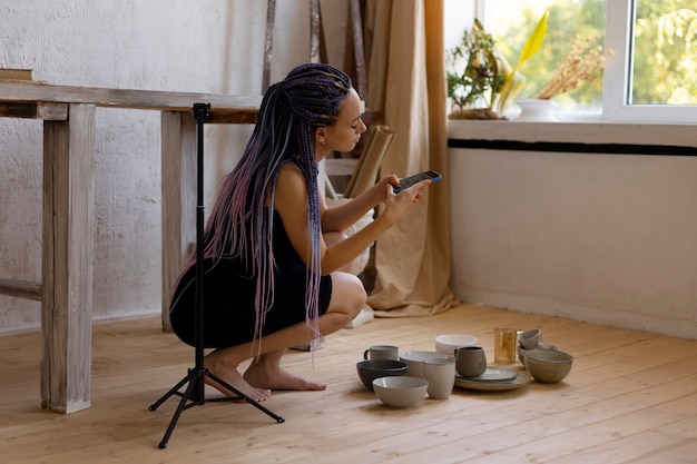 Woman taking photos of ceramic kitchenware at home