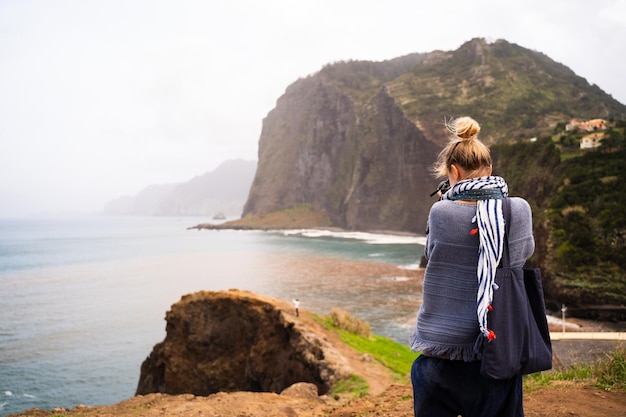 Woman taking photos with a digital camera of the sea from a cliff