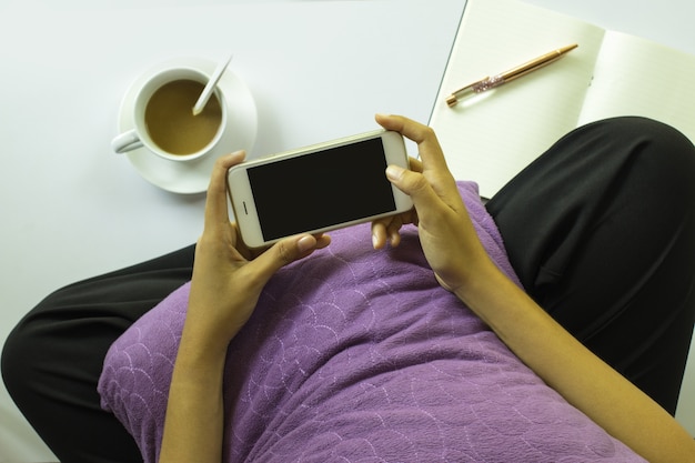 Photo woman taking picture of a cup of coffee with smartphone on white background. top view.