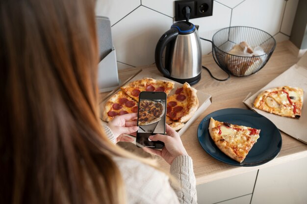 Photo woman taking picture of pizza slice