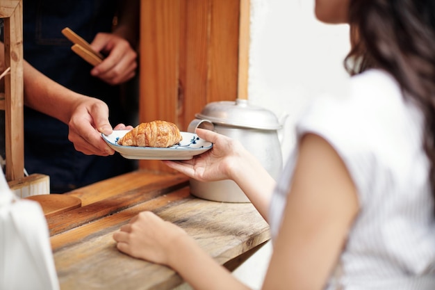 신선한 크루아상과 함께 접시를 먹는 여자