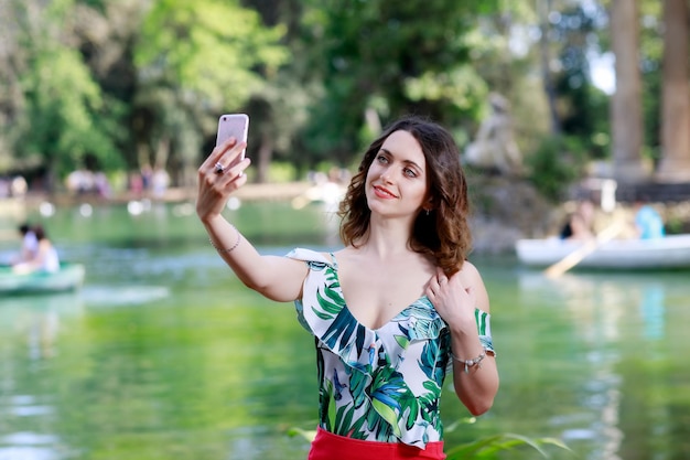 Photo woman taking selfie against pond