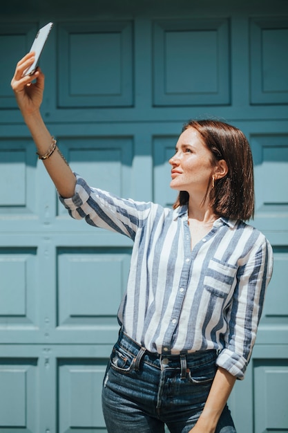 Donna che cattura un selfie da una porta blu