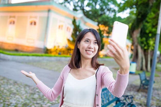 マカオのランドマークで携帯電話でセルフィーを撮っている女性