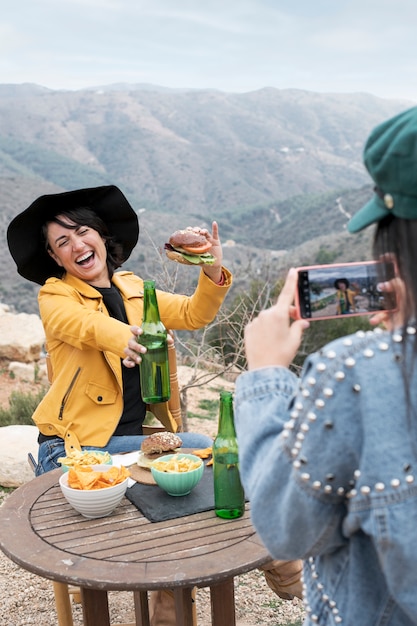 Donna che prende selfie di un amico con hamburger