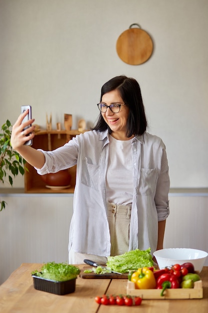 Woman taking selfie or makes a video lesson about cooking, on cellphone