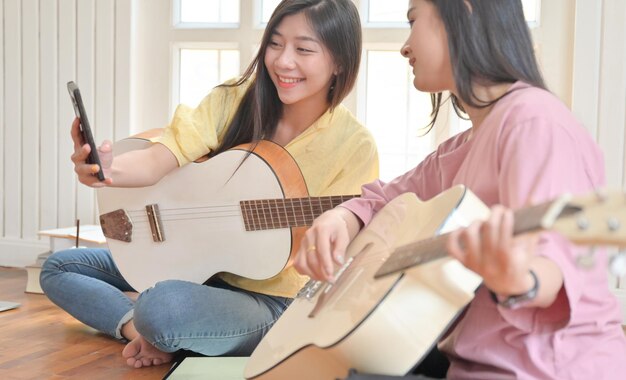 Photo woman taking selfie with friend playing guitar at home