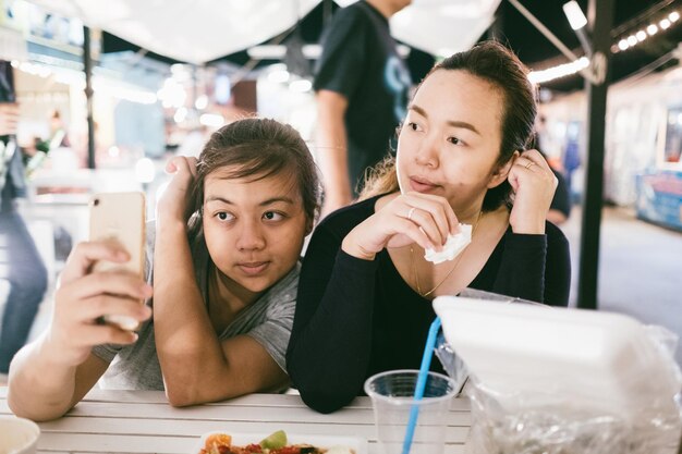 Photo woman taking selfie with friend in restaurant